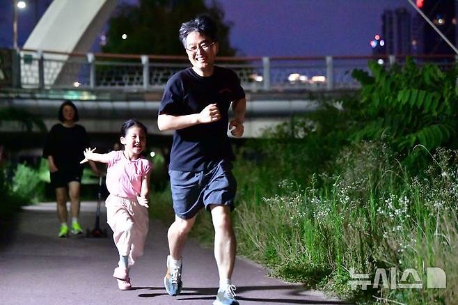 [광주=뉴시스] 이현행 기자= 8일 오후 광주 동구 광주천변 인근에서 더위를 피해 산책나온 아빠와 아이가 잡기놀이를 하고 있다. 2025.07.08 lhh@newsis.com