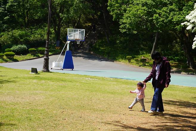 햇살이 비치는 공원, 작은 발이 조심스럽게 땅을 디딘다. 세상을 배워가는 걸음이 조용히 시작된다.