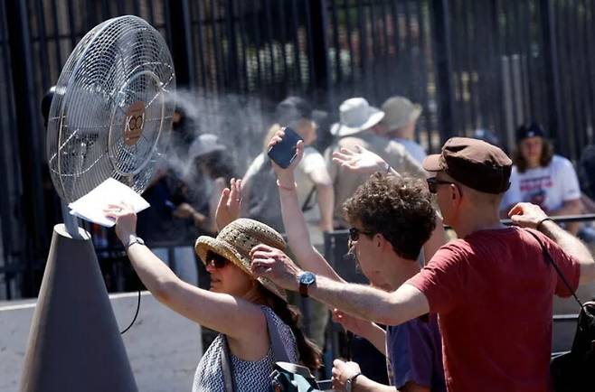폭염이 이어진 지난달 30일 이탈리아 로마 콜레세움 외부에 설치된 선풍기 앞에서 관광객들이 더위를 식히고 있다. 로이터 연합뉴스