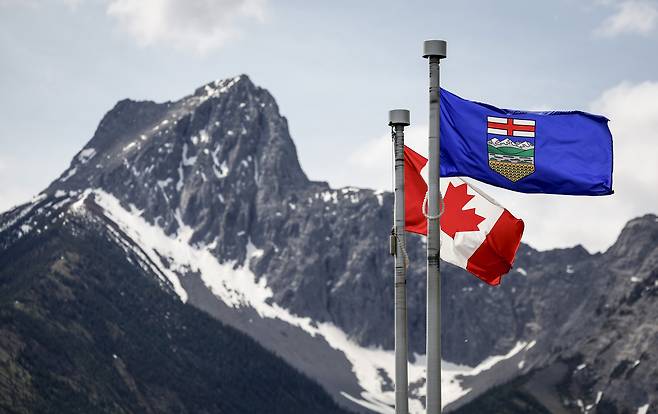 The flag of Canada, left, and the flag of Alberta flap in the breeze with Wedge Mountain in the background at the site of the upcoming G7 summit in Kananaskis, Alberta, on June 2. [AP/YONHAP]