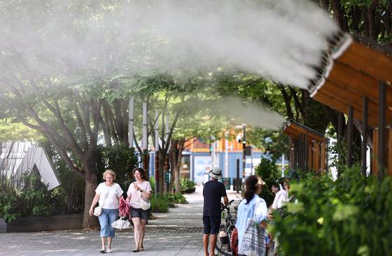 Citizens rest under sprinklers at a park in Seongdong District, eastern Seoul on July 9. [NEWS1]