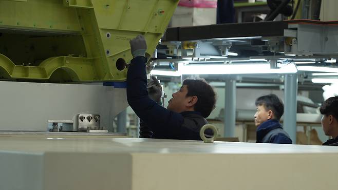 경남 사천 한국항공우주산업(KAI) 고정익 생산 공장에서 현장 엔지니어들이 공정 구역에 배치된 KF-21에 달라붙어 작업을 이어가고 있다. [KAI 제공]