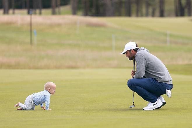 스코티 셰플러가 9일 영국 스코틀랜드 노스베릭의 르네상스 클럽에서 진행한 제네시스 스코티시 오픈 연습라운드에서 그린 위를 기어다니는 아들 베넷을 보며 흐뭇한 표정을 짓고 있다. ｜게티이미지