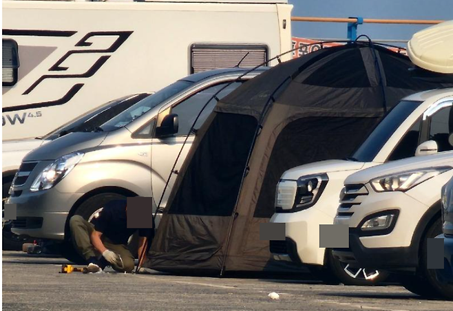 경남 거제 흥남해수욕장 방파제에서 한 캠핑족이 공영주차장 아스팔트에 드릴로 구멍을 뚫고 있다./사진=온라인 커뮤니티 '보배드림'