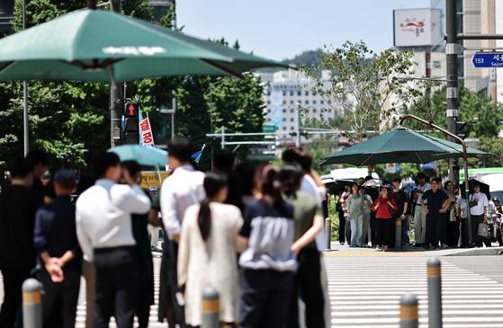 무더위가 이어지는 10일 서울 세종로 사거리에서 시민들이 햇빛 가림막 아래에서 신호를 기다리고 있다. 연합뉴스