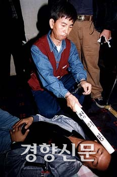 박기서씨가 1996년 10월 26일 경찰의 현장검증에서 백범 암살범 안두희에게 ‘정의봉’을 휘두르는 장면을 재현하고있다. 경향신문자료사진