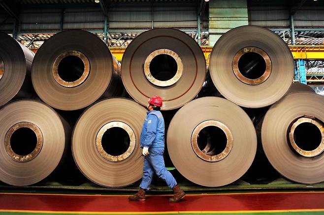 A worker walks by unfinished rolls of stainless steel in a Posco subsidiary in Qingdao city in China's Shandong province. (Getty Images)