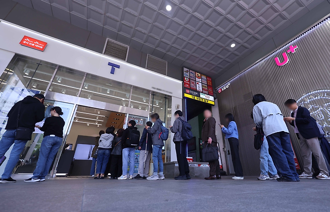 유심 무료교체를 위해 SK텔레콤 대리점에 시민들이 줄을 서서 교체를 기다리고 있다. [연합]