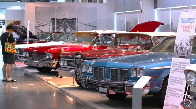 한 관람객이 박정희 전 대통령의 영정 차량으로 사용된 ‘델타88로얄’ 앞에서 휴대폰을 살피고 있다. 남태우 기자