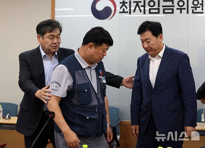 [세종=뉴시스] 강종민 기자 = 최저임금위원회 이인재 위원장이 지난 10일 밤 세종시 정부세종청사에서 2026년도 적용 최저임금안을 합의로 결정한 뒤 류기정 사용자 위원과 류기섭 근로자 위원을 불러 모으고 있다. 내년도 최저임금은 1만 320원으로 결정됐다. 2024.07.11. ppkjm@newsis.com