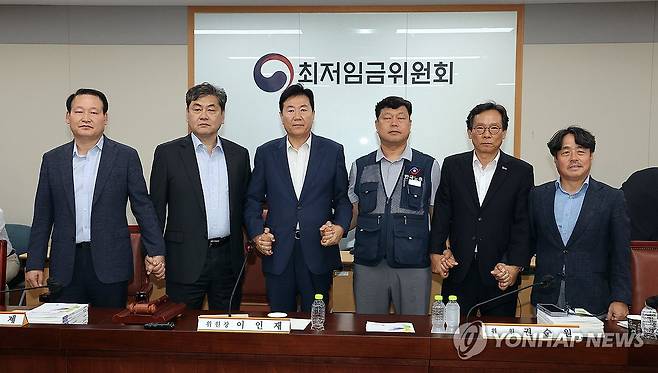 내년 최저임금 시간당 1만320원…17년만에 합의로 결정 (세종=연합뉴스) 배재만 기자 = 이인재 최저임금위원장(왼쪽 두 번째)이 10일 정부세종청사에서 열린 제12차 전원회의에서 내년 최저임금을 시간당 1만320원으로 17년만에 합의로 결정한 뒤 공익위원-사용자위원-근로자위원과 손을 잡고 있다. 2025.7.10 scoop@yna.co.kr