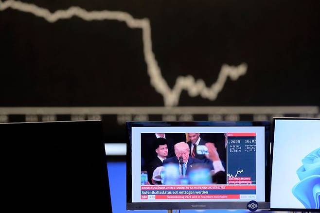 도널드 트럼프 미국 대통령 관련 뉴스가 방송되는 TV 스크린 너머로 주가 지수 그래프가 보이고 있다(자료사진) ⓒAP/뉴시스