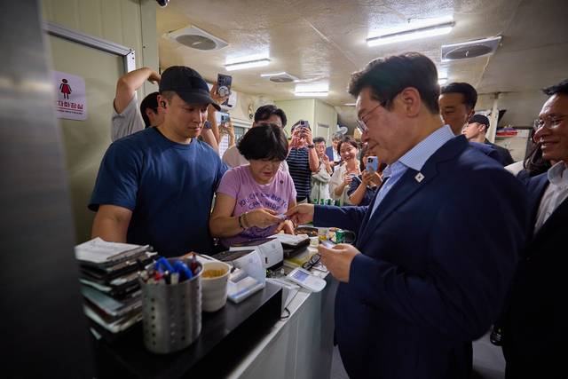 이재명 대통령이 11일 저녁 서울 광화문 인근 한 식당에서 ‘대통령과 외식합니다’ 행사를 갖고 일반 시민, 대통령실 직원과 식사 뒤 계산하고 있다.  연합뉴스
