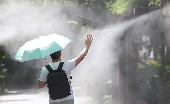 대구 중구 국채보상운동기념공원에 쿨링포그(안개형 냉각수)가 가동 중인 가운데 한 시민이 양산을 들고 이동하고 있다. 온열질환은 빠르게 열을 내리게 하는 게 최선이다. [사진=연합뉴스]