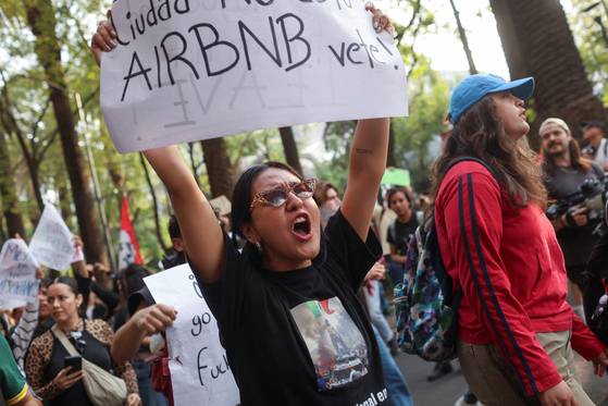 2025년 7월 4일 멕시코시티에 정착한 디지털 유목민들에게 가장 인기 있는 곳 중 하나인 콘데사에서 한 시위자가 '에어비앤비는 떠나라'라고 적힌 현수막을 들고 있다. 해외거주 미국인 협회에 따르면 2023년 기준 해외거주 미국인 500만 명 가운데 20%는 멕시코에 산다. 로이터=연합뉴스