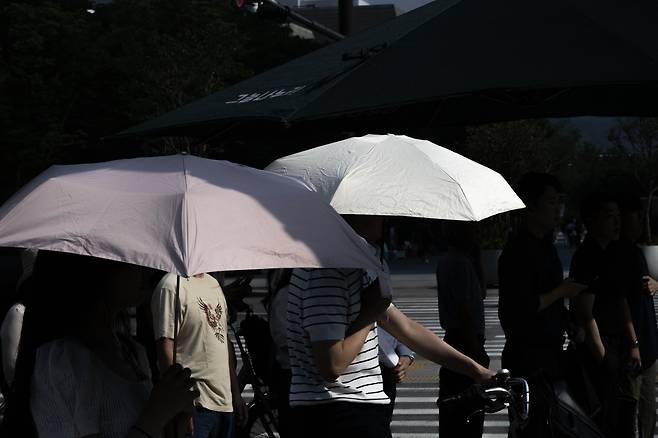 서울 지역에 폭염경보가 발효된 지난 8일 서울 종로구 세종대로 사거리에서 시민들이 양산으로 뜨거운 햇살을 가리며 출근길을 서두르고 있다. 임세준 기자