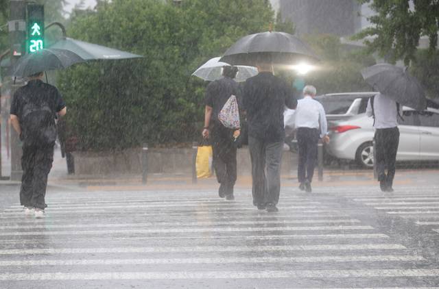 서울 서남권에 호우주의보가 발효된 8일 서울 영등포구 여의도 국회 인근에서 시민들이 우산을 쓰고 횡단보도를 건너고 있다. 연합뉴스