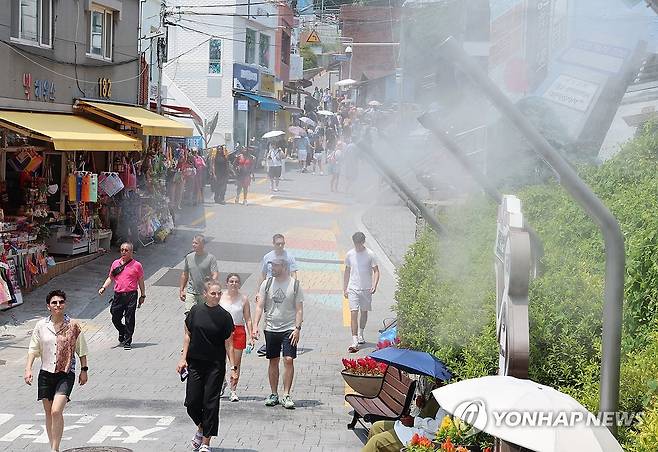 8일 오후 부산 사하구 감천문화마을에서 관광객들이 쿨링포그가 뿜는 물안개를 맞고 있다. [연합뉴스 자료사진]
