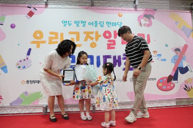 12일 '2025 열두빛깔 어울림 한마당 우리고장 알리기 그리기 대회' 시상식에서 대상을 수상한 강로이(금천초) 학생이 동생으로부터 꽃다발을 받고 있다. 사진=이용민 기자