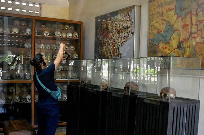 2025년 7월 12일, 프놈펜의 투올슬랭 대학살 박물관에서 한 관광객이 크메르루주 정권 희생자들의 두개골 옆에서 사진을 찍고 있다. /연합뉴스