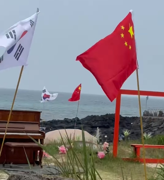 제주 우도면의 한 해안도로변에 중국 국기인 오성홍기(오른쪽)와 태극기가 나란히 꽂혀 있다. 한 누리꾼이 8일 촬영했다고 주장하며 사회관계망서비스(SNS) 스레드에 올린 영상의 한 장면. 스레드 캡처