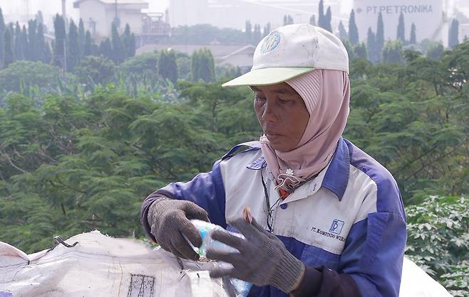 유윤이 쓰레기산 한 편에 놓인 포대 앞에서 모아 온 플라스틱을 정리하고 있다. 유혜민 감독 제공