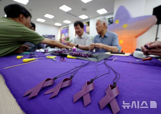 [서울=뉴시스] 김진아 기자 = 10·29 이태원참사 유가족협의회·시민대책회의를 비롯한 참석자들이 12일 서울 종로구 별들의집에서 열린 10.29 이태원 참사, 함께 만드는 1000일 '1000개의 별목걸이 함께 만들어요'에서 보라리본 목걸이를 만들고 있다. 2025.07.12. bluesoda@newsis.com