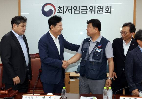 최저임금위원회 사용자위원 운영위원인 류기정 한국경영자총협회 전무(왼쪽)와 근로자위원 운영위원인 류기섭 한국노총 사무총장이 10일 정부세종청사에서 열린 제12차 전원회의에서 내년 최저임금을 시간당 1만320원으로 17년 만에 합의로 결정한 뒤 악수하고 있다. 왼쪽은 이인재 위원장, 오른쪽은 이명로 중소기업중앙회 인력정책본부장. 2025.7.11