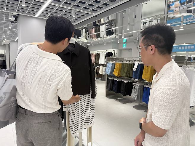 Fashion stylist Rams recommends outfits to Jeremy Aban during a shopping tour at Musinsa Standard in Myeong-dong, central Seoul. [WOO JI-WON]