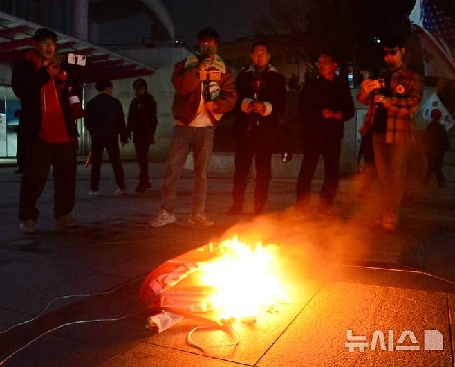 [청주=뉴시스] 서주영 기자 = 11일 충북대학교에서 보수 성향 유튜버가 탄핵 찬성 집회 측이 현장에 놓고간 현수막을 불태우고 있다. 2025.03.11. juyeong@newsis.com