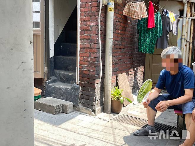 [서울=뉴시스]이채은 인턴기자 = 지난 8일 폭염 경보가 발효 중인 서울 영등포구 쪽방촌에서 한 주민이 집안 내부의 찜통더위를 피해 골목에 나와 앉아있다. 2025.07.08