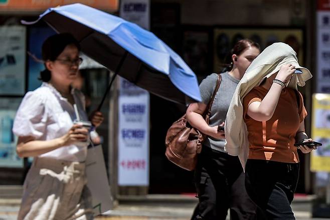 서울 중구 을지로3가역 인근에서 한 시민이 겉옷으로 햇빛을 가린 채 이동하고 있다. [사진 | 뉴시스]