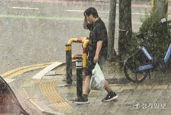 경기도내 일부 지역에 호우주의보가 발령됐던 지난 8일 오후 수원특례시 장안구 거리 일대에 기습 폭우가 내리는 가운데 한 시민이 길을 걷고 있는 모습. 홍기웅 기자