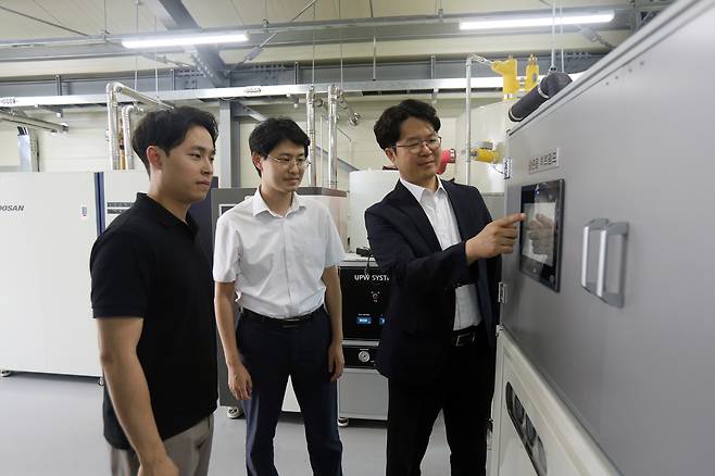 온실 3중 열병합발전 시스템을 개발한 이상민(오른쪽) 한국기계연구원 미래농생명공학연구단장이 히트펌프 장비를 살펴보고 있다.[한국기계연구원 제공]