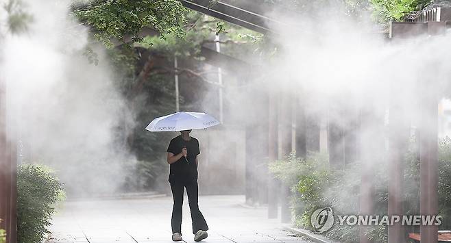 찜통더위 대구에 폭염경보가 발효 중이었던 6월 30일 대구 중구 국채보상운동기념공원에 쿨링포그(안개형 냉각수)가 가동 중인 가운데 한 시민이 양산을 들고 이동하고 있다. [연합뉴스 자료사진]