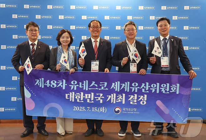 2026년 세계유산위원회 개최지로 부산이 확정된 16일 새벽(한국시간) 프랑스 파리 유네스코 본부에서 최응천 국가유산청장(왼쪽부터)과 박상미 주유네스코 대표부 대사, 이준승 부산시 행정부시장, 국민의힘 박정하 의원, 더불어민주당 조계원 의원이 플래카드를 들고 기념 촬영을 하고 있다. 2025.7.16/뉴스1 ⓒ News1 이준성 기자