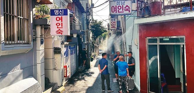 동자동 쪽방 주민들이 폭염 열기를 누그러뜨리기 위해 설치한 골목길 쿨링포그 근처에서 이야기를 나누고 있다.