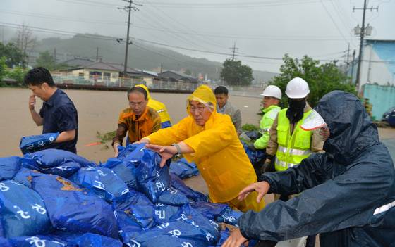 17일 오전 이용록 홍성군수(노란색 우의)가 폭우로 범람한 갈산천에서 주민들과 함께 긴급 복구 작업을 벌이고 있다. [사진 홍성군]