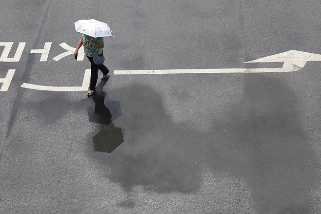 양산을 든 행인이 장맛비로 젖은 땅을 걷고 있다. 연합뉴스
