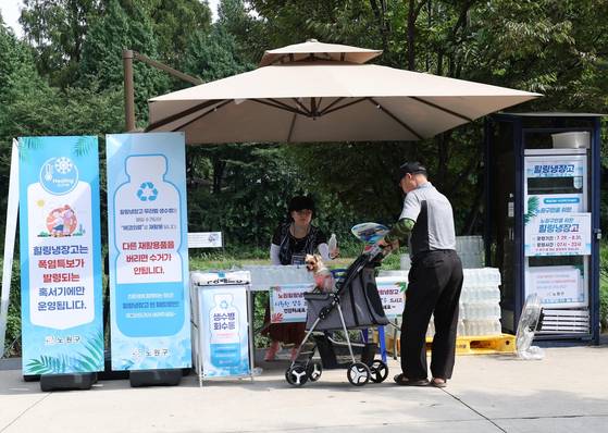 A Nowon district official hands out a free bottle of water to a passerby on a street in Nowon District, northern Seoul, last summer. [NOWON DISTRICT OFFICE]