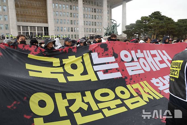 [서울=뉴시스] 조성봉 기자 = 민주노총 공공운수노조 화물연대본부 조합원들이 지난해 11월 26일 오후 서울 여의도 국회 본청 앞 계단에서 ‘안전운임제 입법’을 촉구하며 기습시위를 하고 있다.화물연대는 안전운임제 항구적 재도입, 공정한 안전운임위원회 구성 및 운영을 위한 대표위원 간 동수 보장, 안전운임의 구체적 현장 적용과 안전한 노동환경을 위한 부대조항의 법 근거 마련을 요구했다. 2024.11.26. suncho21@newsis.com