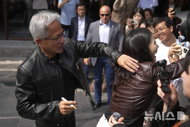 [베이징=AP/뉴시스] 젠슨 황 엔비디아 최고경영자(CEO)가 16일(현지 시간) 중국 베이징에서 열린 제3회 중국 국제 공급망 촉진 박람회(CISCE) 참석 후 만다린 오리엔탈 첸먼 호텔에서 기자회견하면서 한 기자의 가죽 재킷에 사인을 해주고 있다. 2025.07.16.