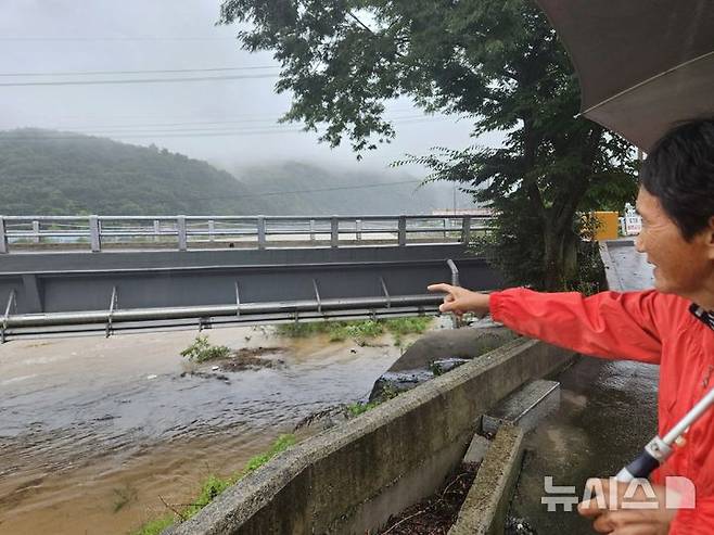 [청주=뉴시스] 안성수 기자 = 17일 충북 괴산군 칠성면 외사리에서 주민 전영숙(70)씨가 지난 2023년 괴산댐 수해로 잠겼던 수전교를 가리키고 있다. 2025.7.17. hugahn@newsis.com