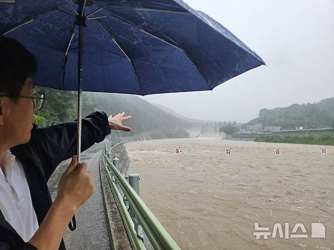 [괴산=뉴시스] 안성수 기자 = 17일 충북 괴산군 칠성면 외사리 주민이 방류 중인 괴산댐을 가리키고 있다. 외사리는 지난 2023년 괴산댐 월류로 수해 피해를 크게 입었다. 2025.7.17. hugahn@newsis.com