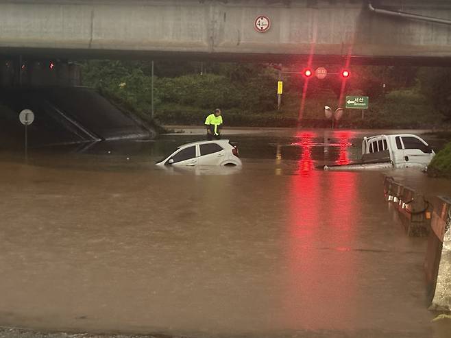 17일 오전 호우경보가 내려진 충남 서산시 운산면 운산교차로 지하차도에 침수가 발생해 차량 2대가 물에 잠겨있는 가운데 스파크 운전자가 차 위에서 구조를 기다리고 있다. 독자 제공