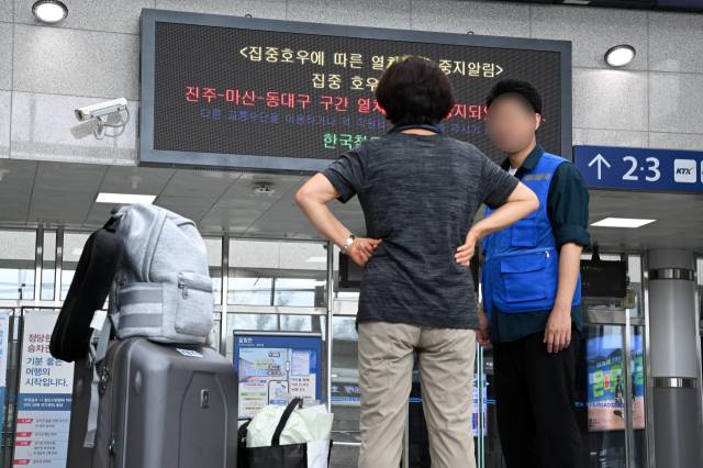 연일 이어진 폭우 여파로 열차와 항공 등의 운행이 차질을 빚고 있는 가운데 18일 창원중앙역을 찾은 한 이용객이 철도공사 직원의 운행중지 안내 설명을 듣고 있다./성승건 기자/