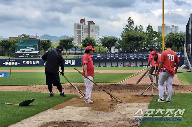 18일 광주기아챔피언스필드. 그라운드 정비 관계자들이 흙으로 젖은 땅을 덮고 있다. 광주=김민경 기자