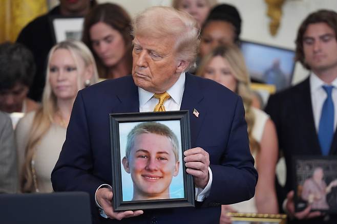 16일 미국 워싱턴 DC 백악관 이스트룸에서 열린 'HALT 펜타닐 법' 서명식에서 도널드 트럼프(가운데) 대통령이 펜타닐 중독으로 사망한 미국인의 사진을 들어보이고 있다. 이날 서명식에는 펜타닐 오남용으로 사망한 이들의 유가족들이 참석했다. 지난 10년간 미국인 약 45만 명이 펜타닐 오남용으로 사망했고, 수백만 명이 중독된 것으로 알려졌다. /AP 연합뉴스