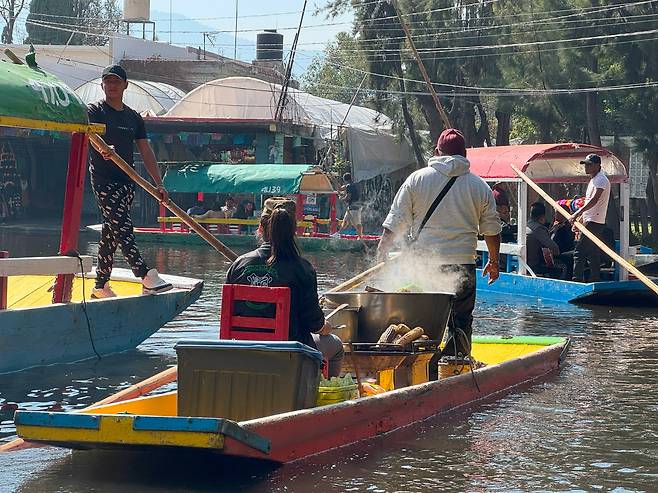 소치밀코(Xochimilco) 운하의 옥수수 판매 보트. 관광용 배의 주변에 음식을 파는 보트, 맥주 보트, 기념품 보트, 꽃을 파는 보트, 음악을 연주하는 보트 등이 계속해서 지나간다.
