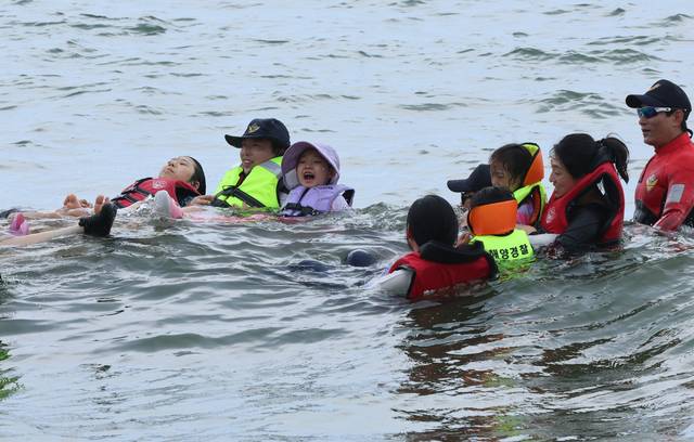 부산 수영구 광안리해수욕장. 사진은 지난 16일 ‘부산해경 생존수영 체험교실’에서 어린이들이 인명구조요원 자격증을 소지한 해양경찰의 도움을 받아 바다 생존수영법을 배우고 있다. 연합뉴스.